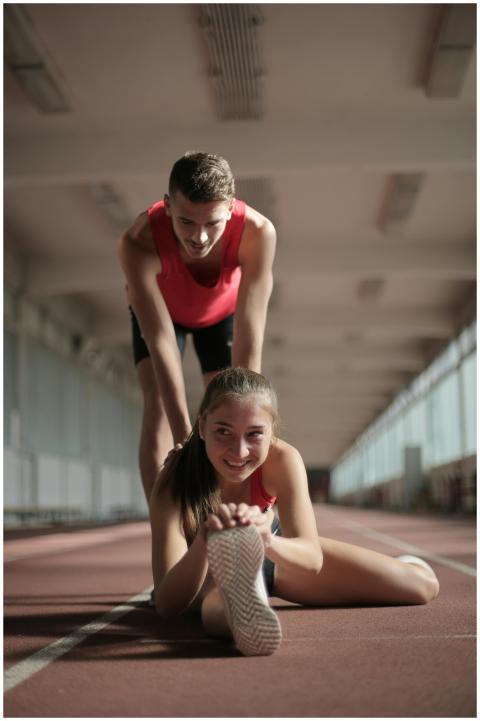 Athletic man and woman stretching together indoors
