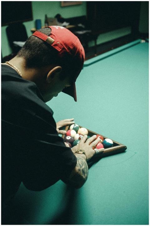 A man arranging billiard balls on a pool table. In