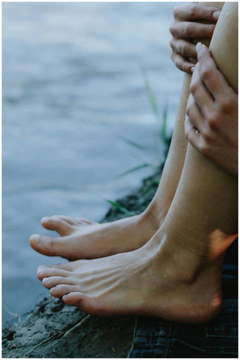 Close-up of bare feet on the shore, embracing tran