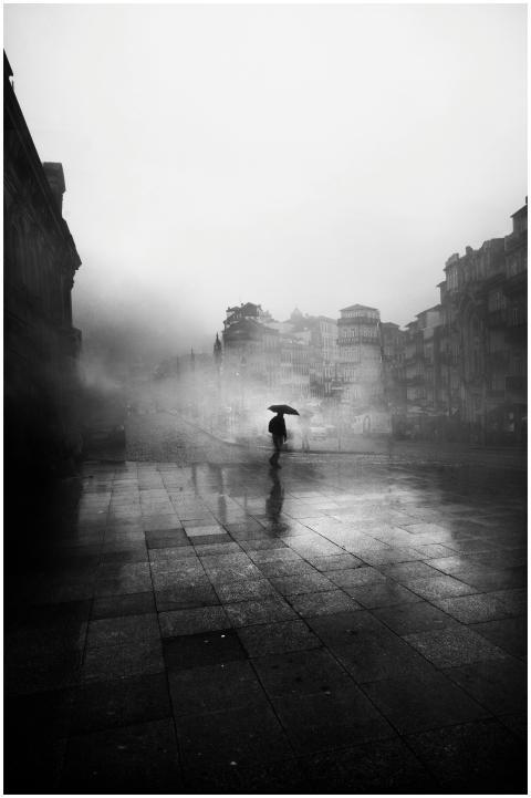 A lone figure with an umbrella in a foggy city, cr