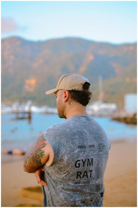 Rear view of a tattooed man in a cap overlooking a