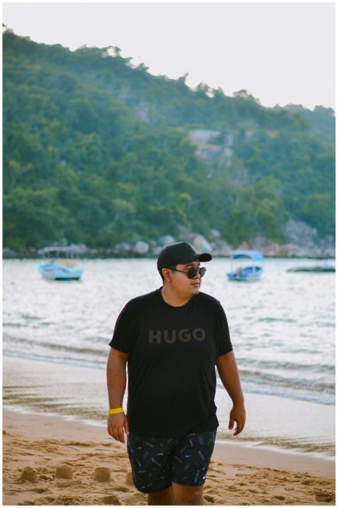 Man in casual wear walking on a beach with boats a