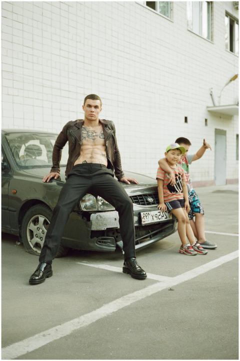 Man in stylish attire poses with kids next to dama