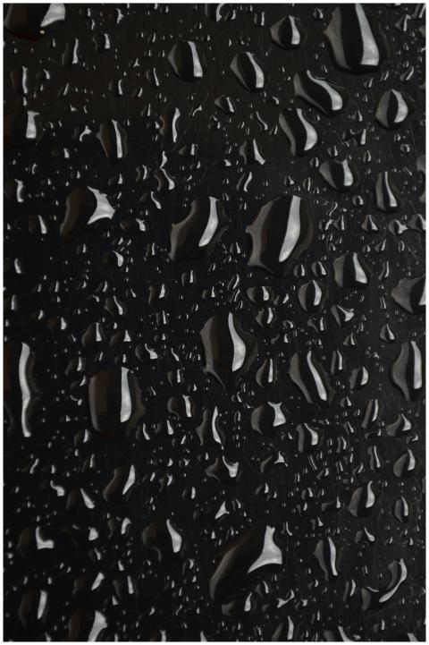 Macro shot of water droplets on a black surface, s