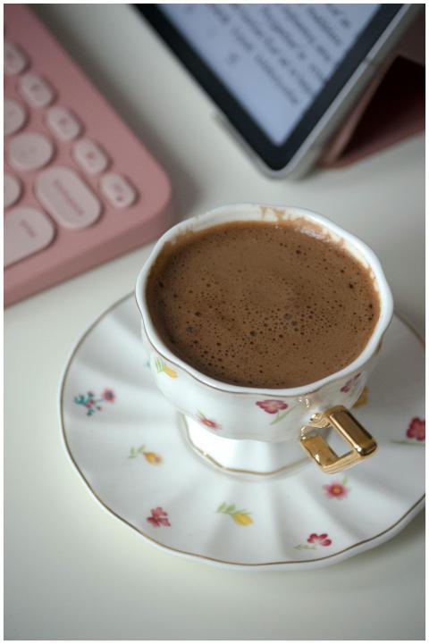 A close-up of a floral coffee cup with a modern pi