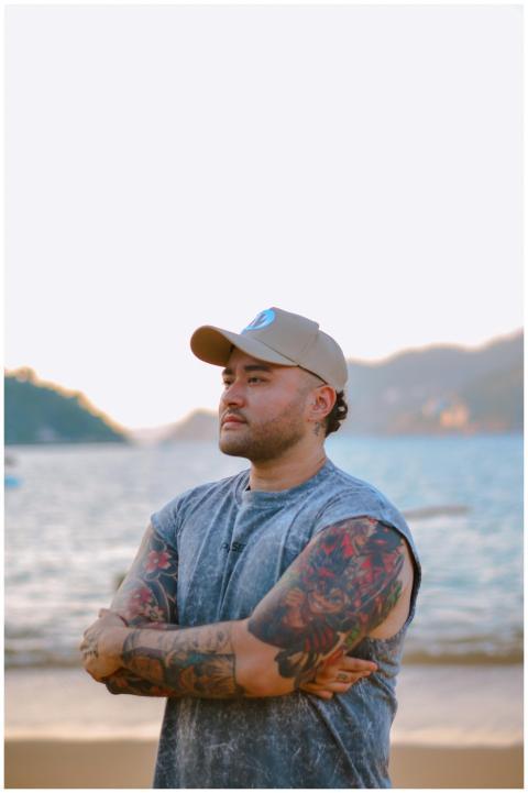 A tattooed man in a cap standing confidently by th