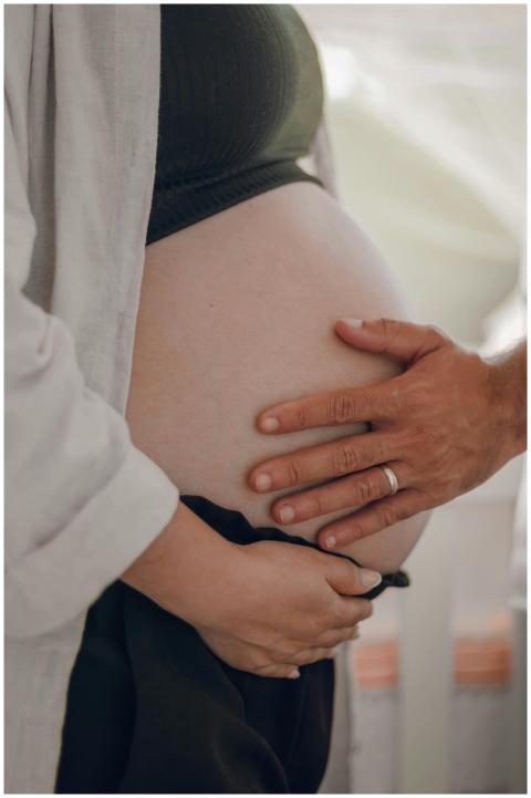 A pregnant woman is tenderly touching her belly wi