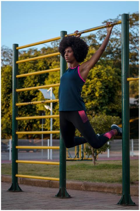 A young woman performs exercises on outdoor pull-u