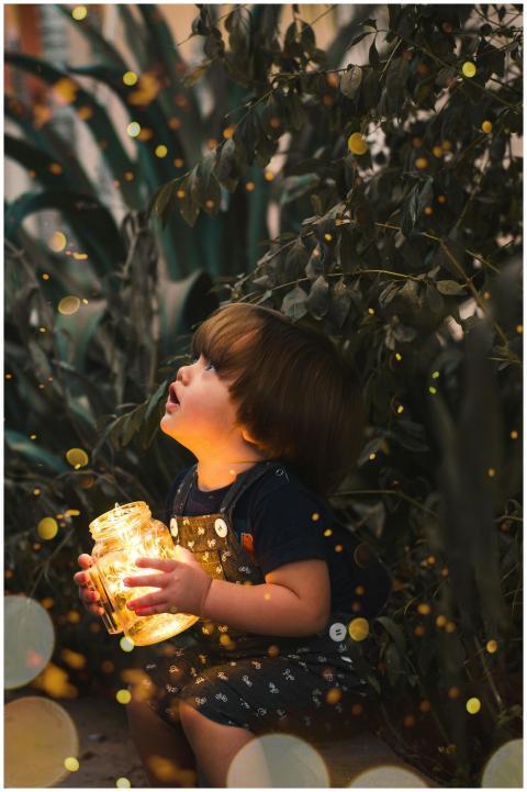 A young child gazes in wonder while holding a jar