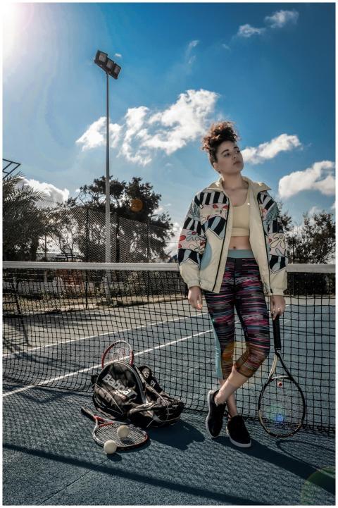 Stylish woman posing on outdoor tennis court with