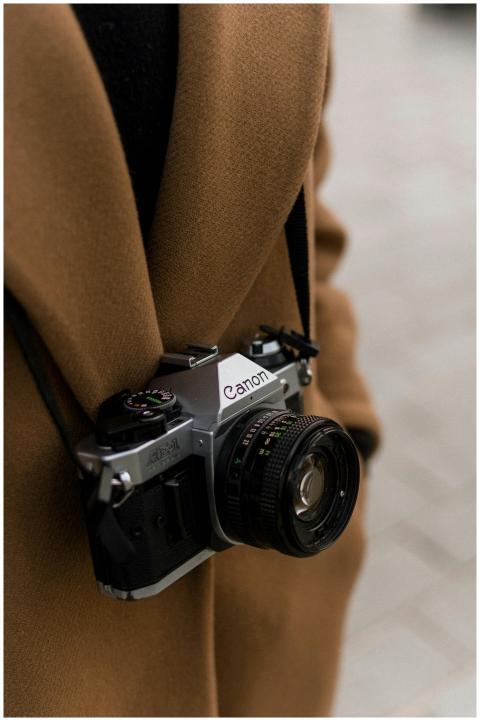 A vintage Canon film camera worn by a photographer