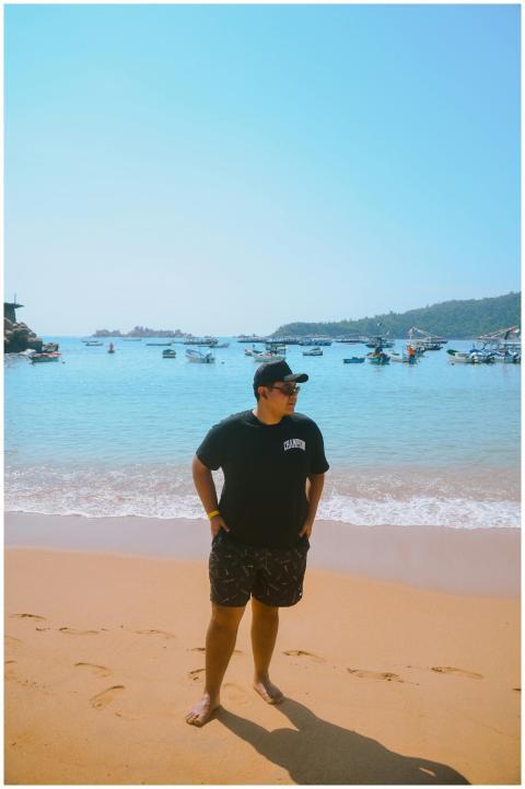 Casual young man standing on a sunny beach with bo