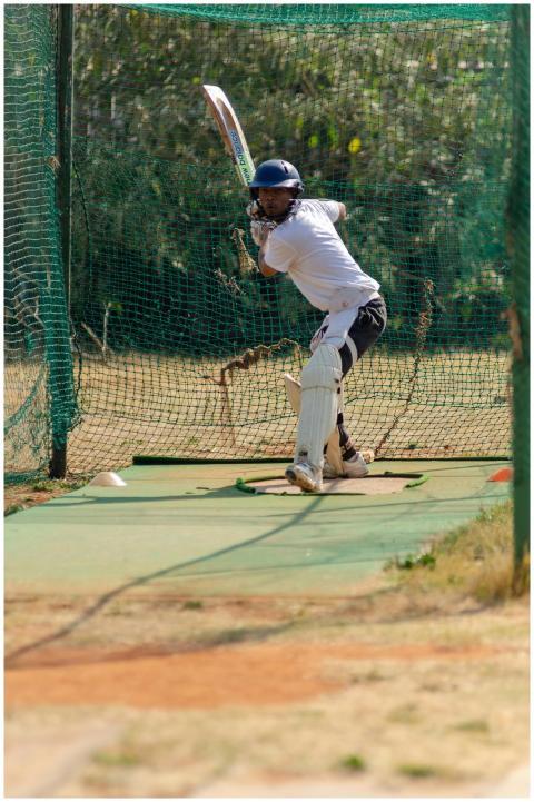 A cricket player practicing a sweep shot in outdoo