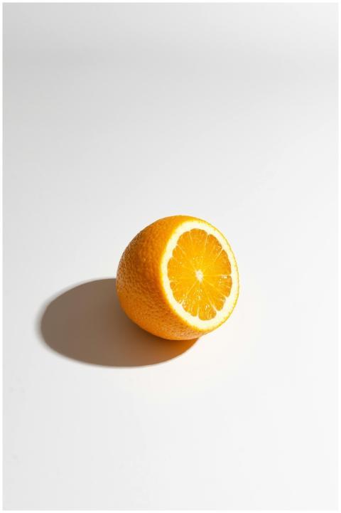 A single fresh orange slice casting a shadow on a