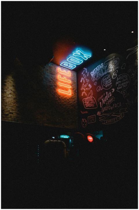 Neon 'LIFE BOX' sign glowing in a dimly lit urban