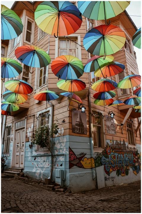 Vibrant umbrellas float above a graffitied street