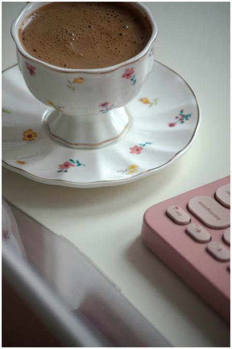 A floral-patterned tea cup and saucer next to a pi