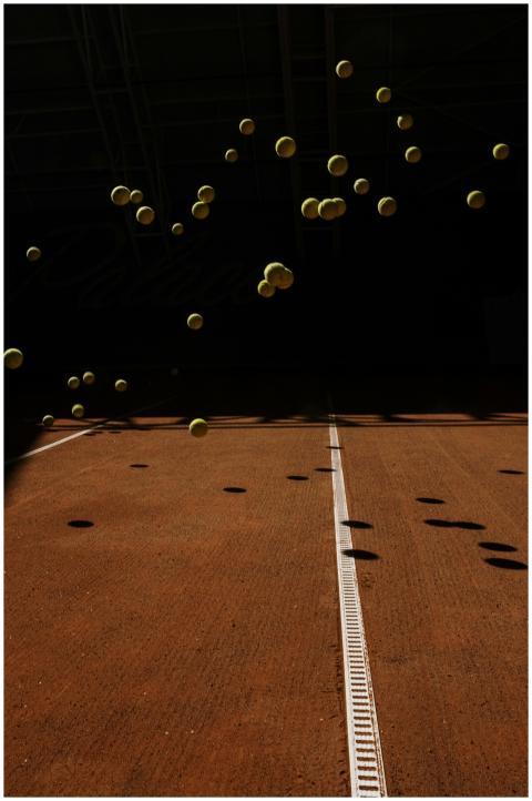 Tennis balls in motion creating shadows on a clay