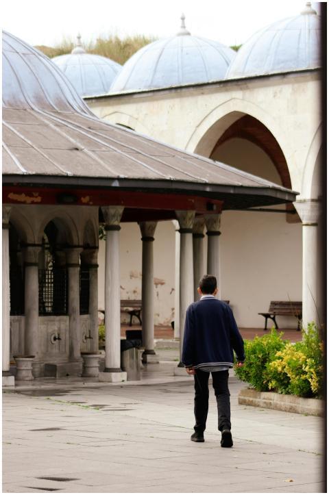 Man walks through a historic courtyard with arches