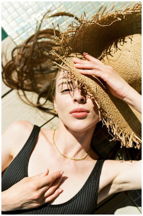 A woman relaxes outdoors with a straw hat, embraci