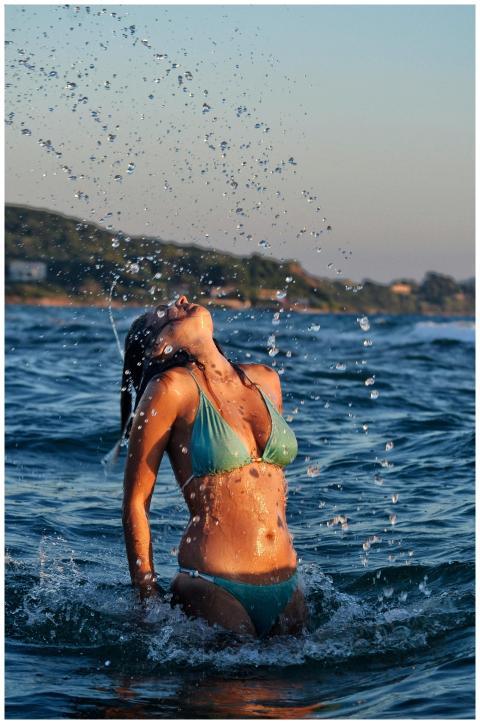 A woman in a bikini enjoying the ocean waves at su