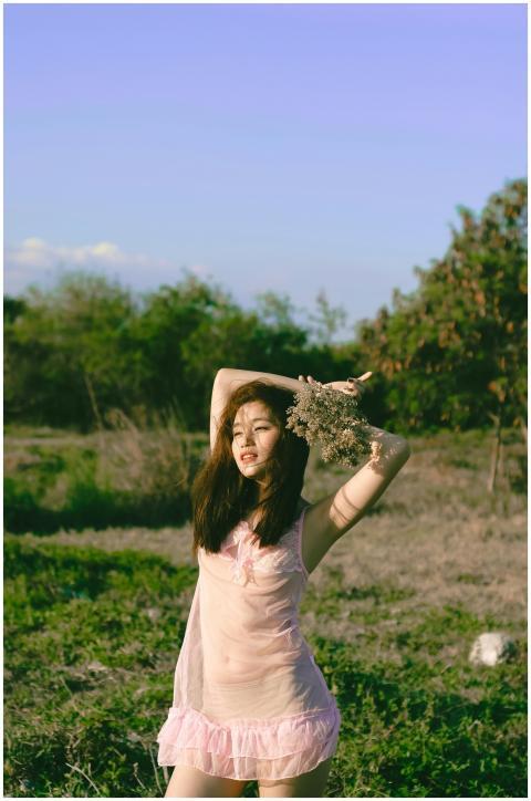 Asian woman in a pink dress posing joyfully with a