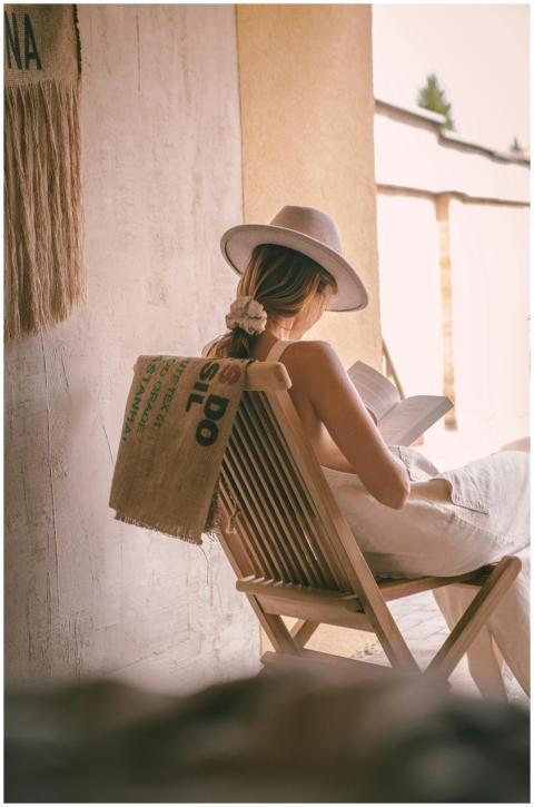 Woman in hat reading a book outdoors, embodying re