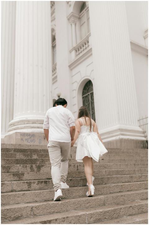 A couple elegantly ascends stone steps of a histor