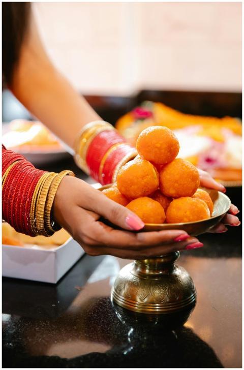 Woman presenting Indian sweets on a brass plate, s