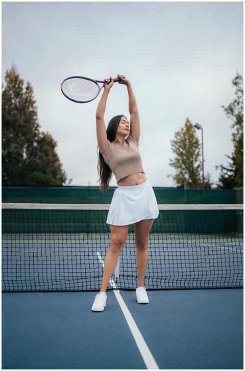 Athletic woman holding tennis racket, arms raised