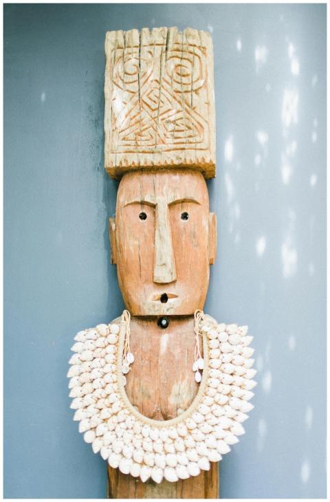 Wooden tribal sculpture adorned with a detailed sh