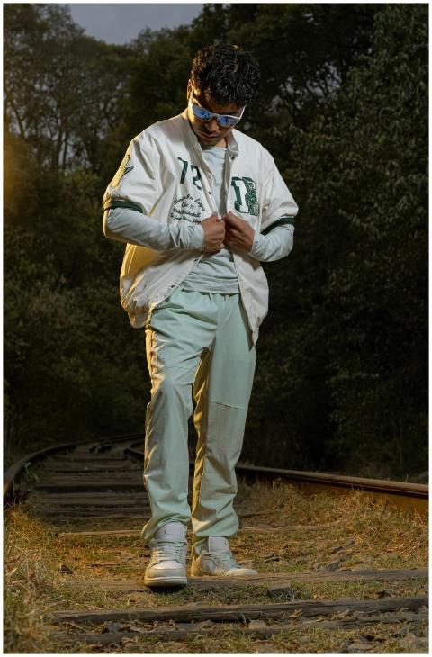 Stylish man in white jacket standing on railway tr