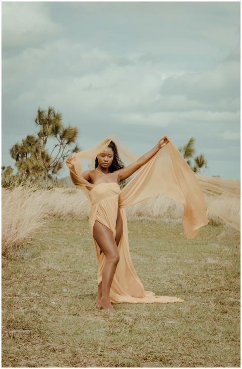 A beautiful woman in a flowing dress poses amidst