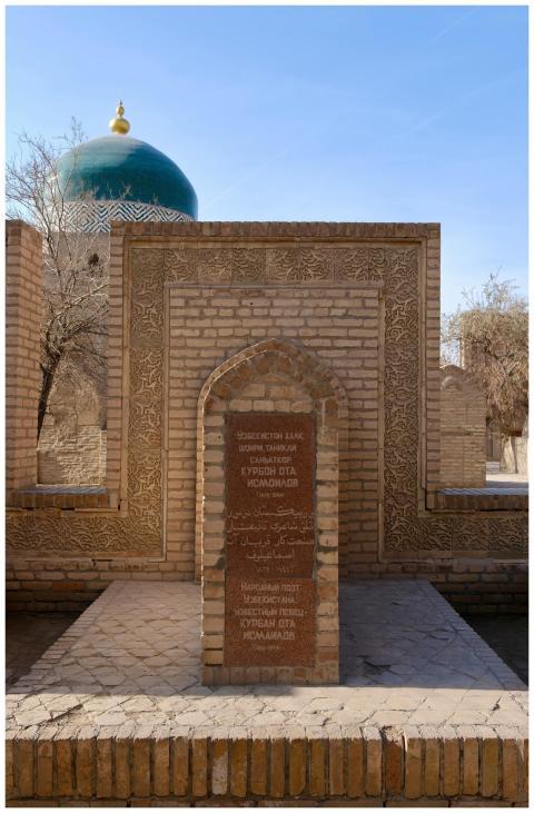 A historic brick archway with a green dome in a su