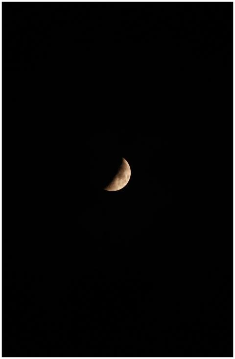 A crescent moon shines brightly against a dark sky