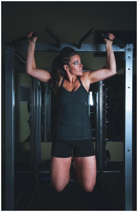 A strong woman performs a pull-up exercise in a mo