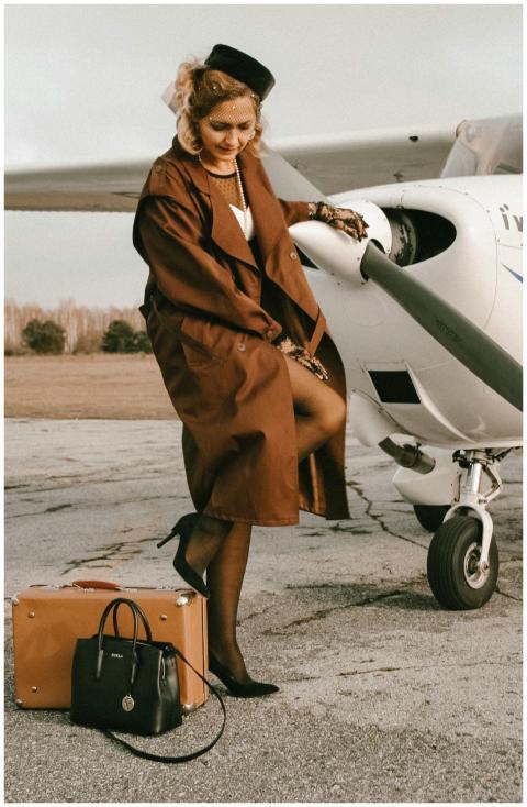 Elegant woman in vintage attire standing by a prop