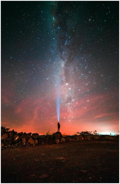 A person shines a light towards the Milky Way in t