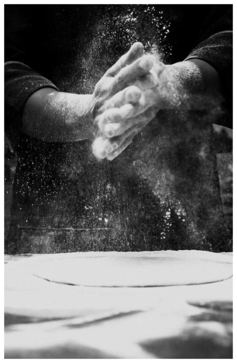 Black and white photo of a chef clapping flour in