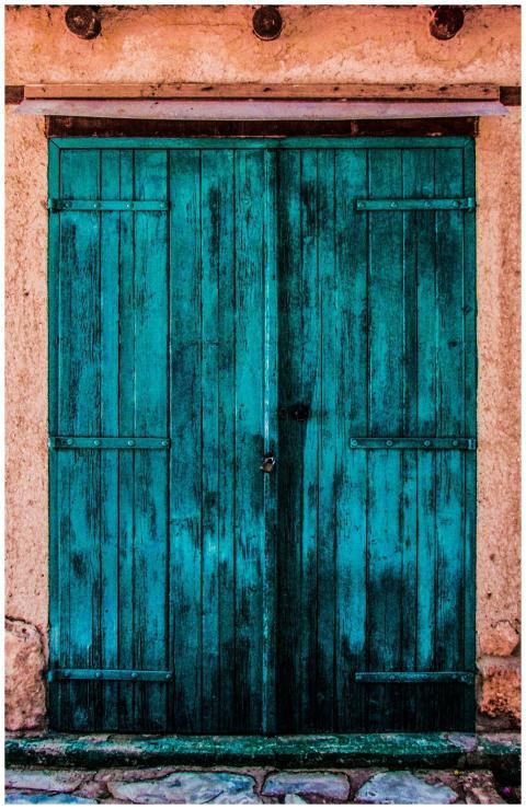 A vibrant, rustic blue wooden door on a textured,