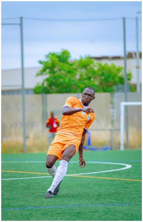Soccer player in orange uniform on field mid-actio