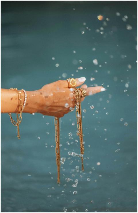 A graceful hand wearing gold bracelets and rings i