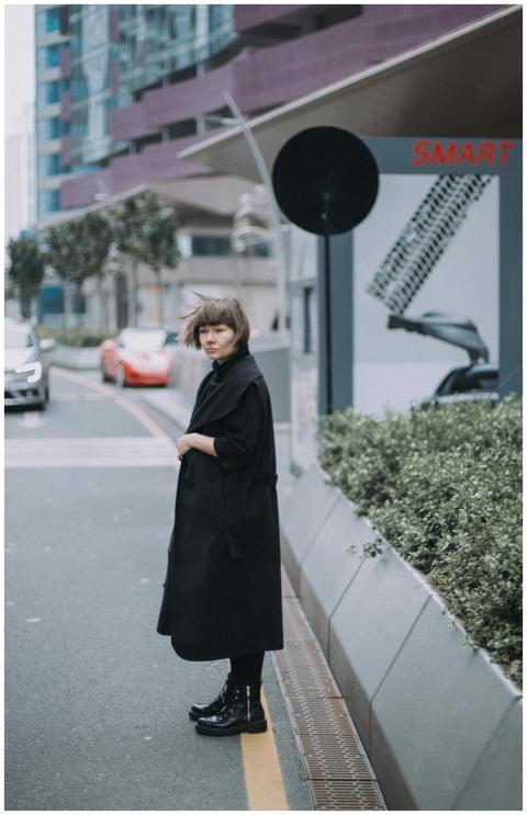 Young woman in black coat standing stylishly on an