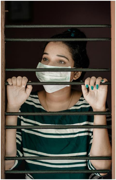 A woman wearing a face mask looks through window b