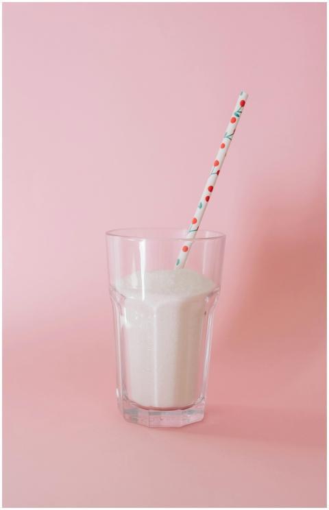 A glass of milk with a decorative straw set agains
