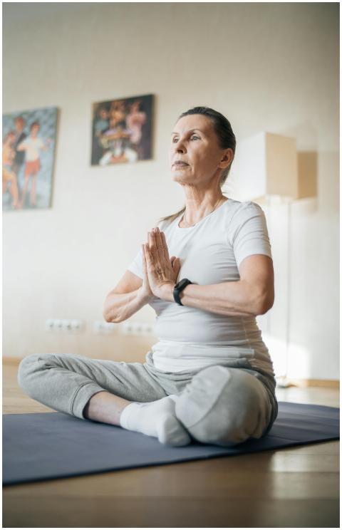 Elderly woman practicing yoga at home, focusing on