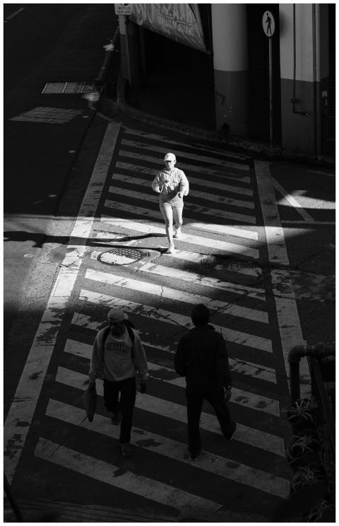Moody black and white photo of pedestrians crossin