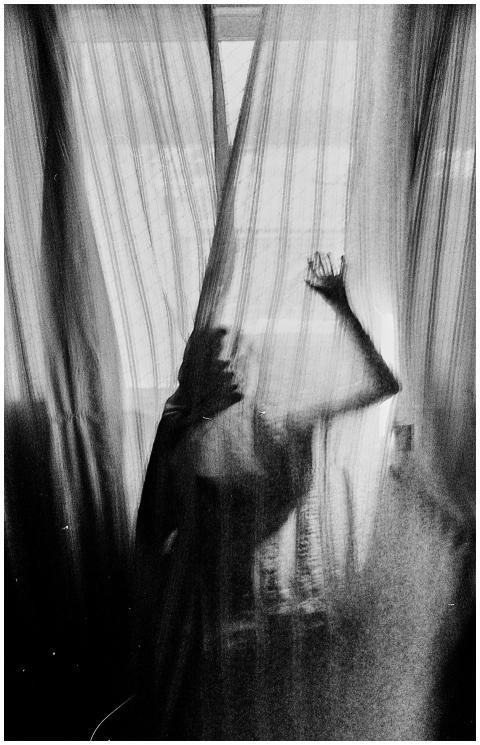Silhouette of a person behind sheer curtains creat