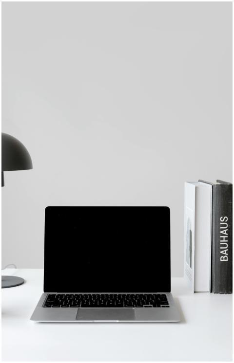 A clean, modern workspace with a laptop, desk lamp