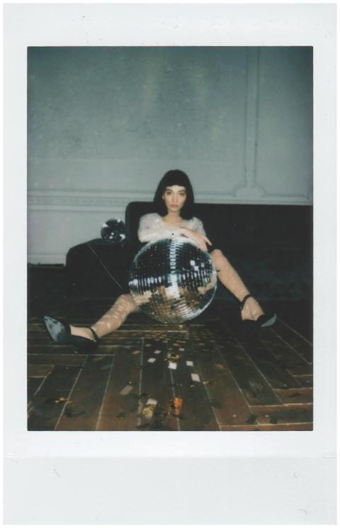 Fashionable woman posing with a disco ball indoors